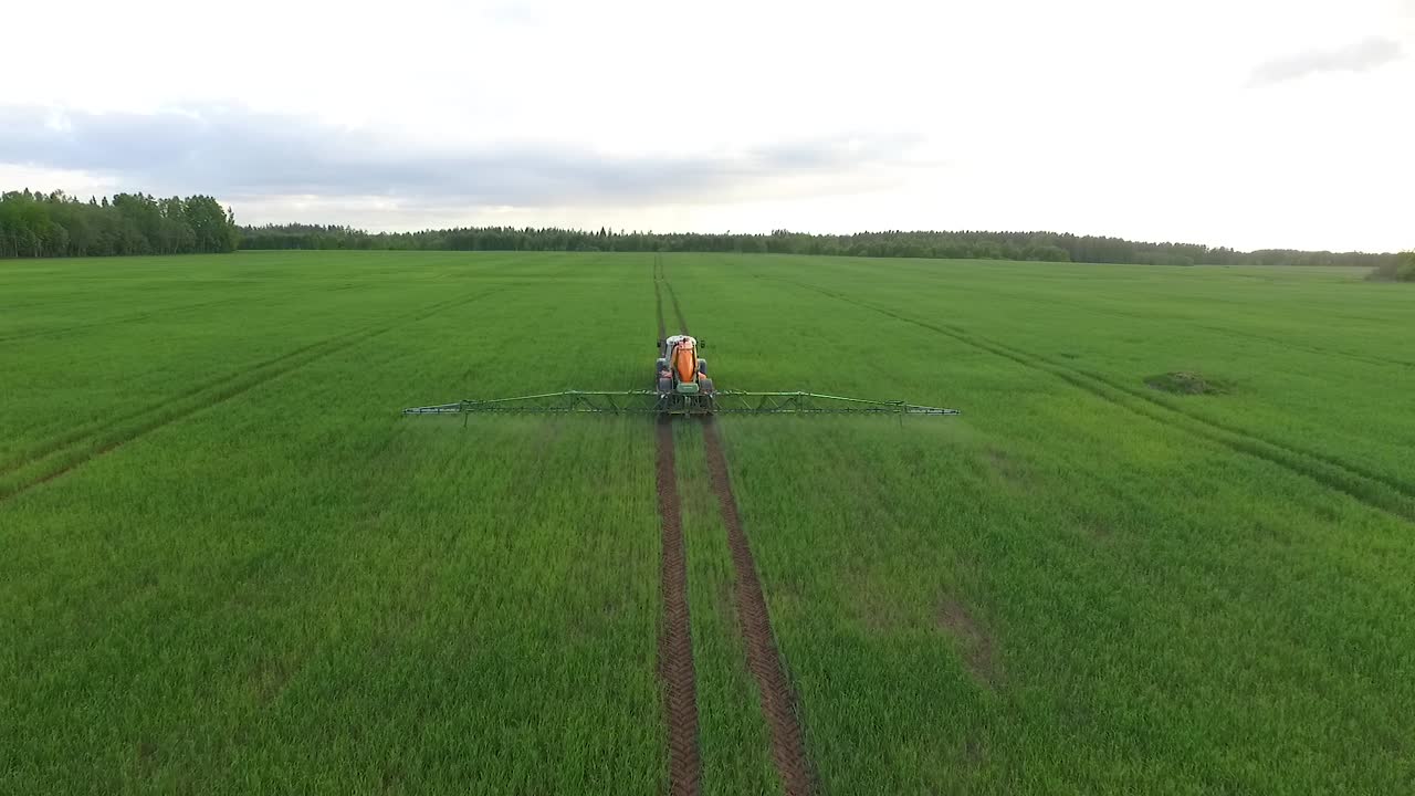 Irrorazione di pesticidi e fertilizzanti sul campo, vista aerea con trattore