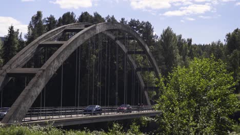 los coches y las bicicletas circulan sobre un río en un pequeño puente.