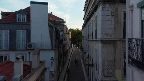 Drone-camera-flying-through-narrow-street-in-town-center.-Evening-elevated-footage.-Lisbon,-capital-of-Portugal.