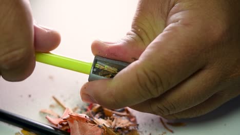 footage of hands slowly sharpening a pencil and some coloured pencils with a wedge pencil sharpener