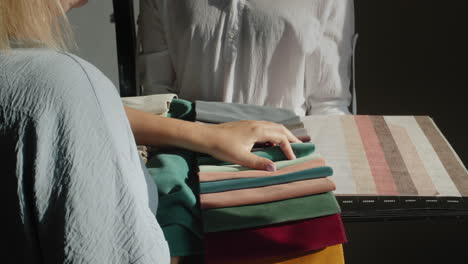 a woman chooses textiles for repair in the house, compares with images of wallpaper, selects color and shade