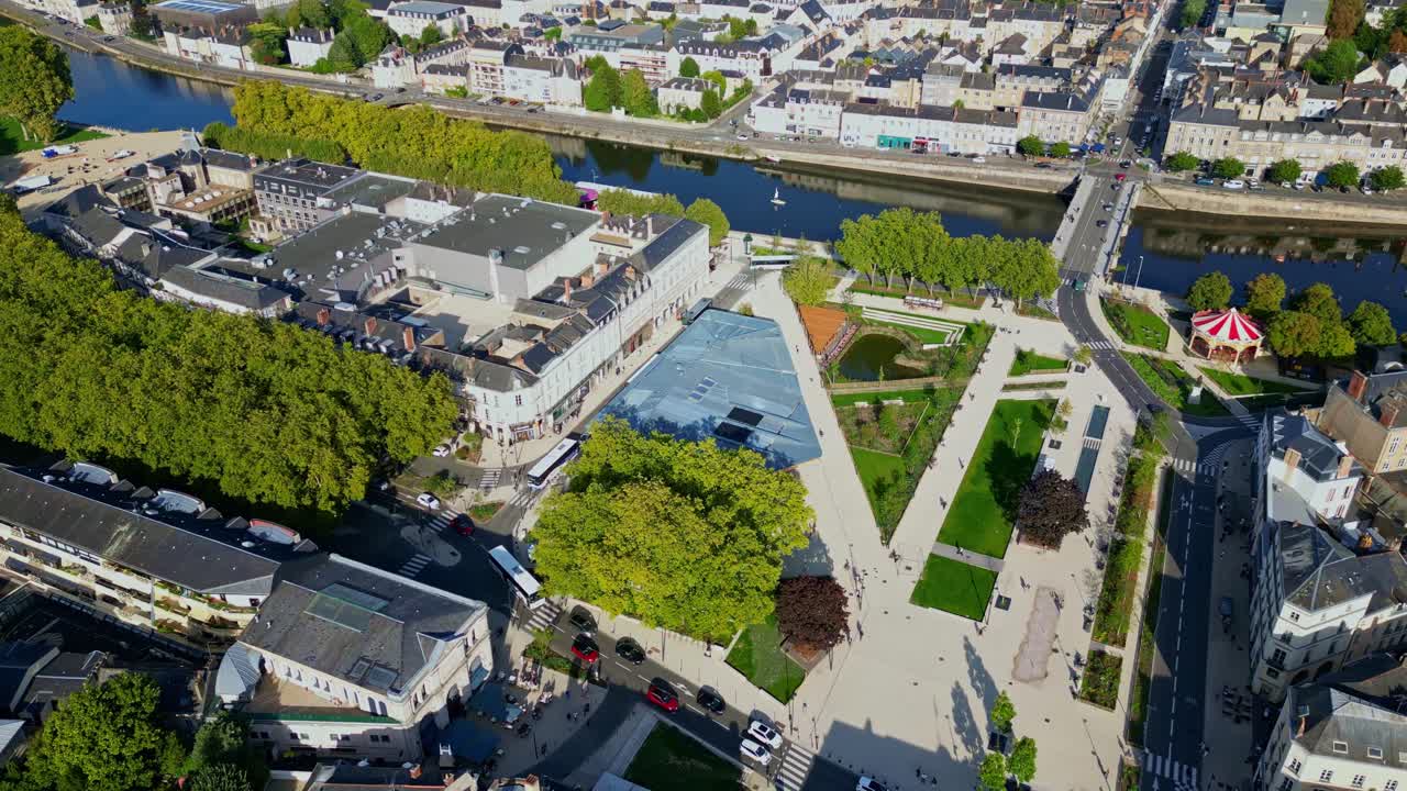 A drone panning shot shows Place du 11 Novembre in Laval, with the Mayenne river, city buildings, and traffic visible in the background