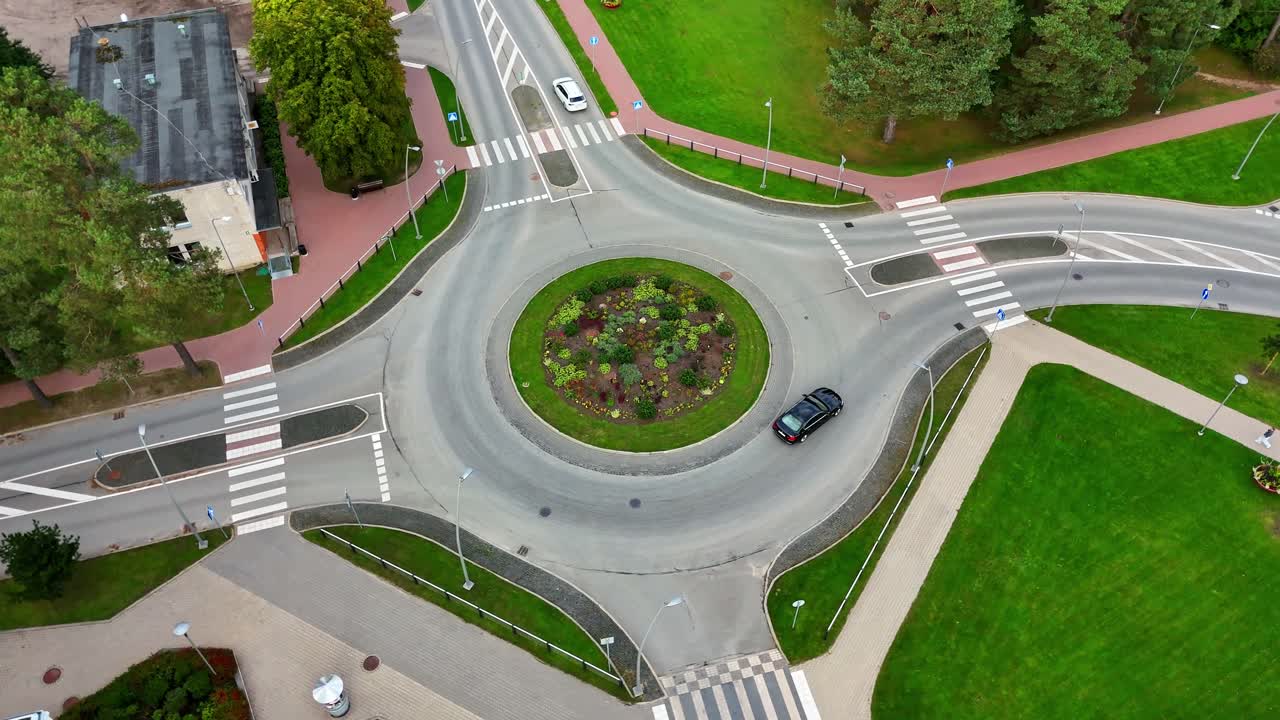 Drone of orbit of roundabout and residential area with roads crossing green spaces, centered