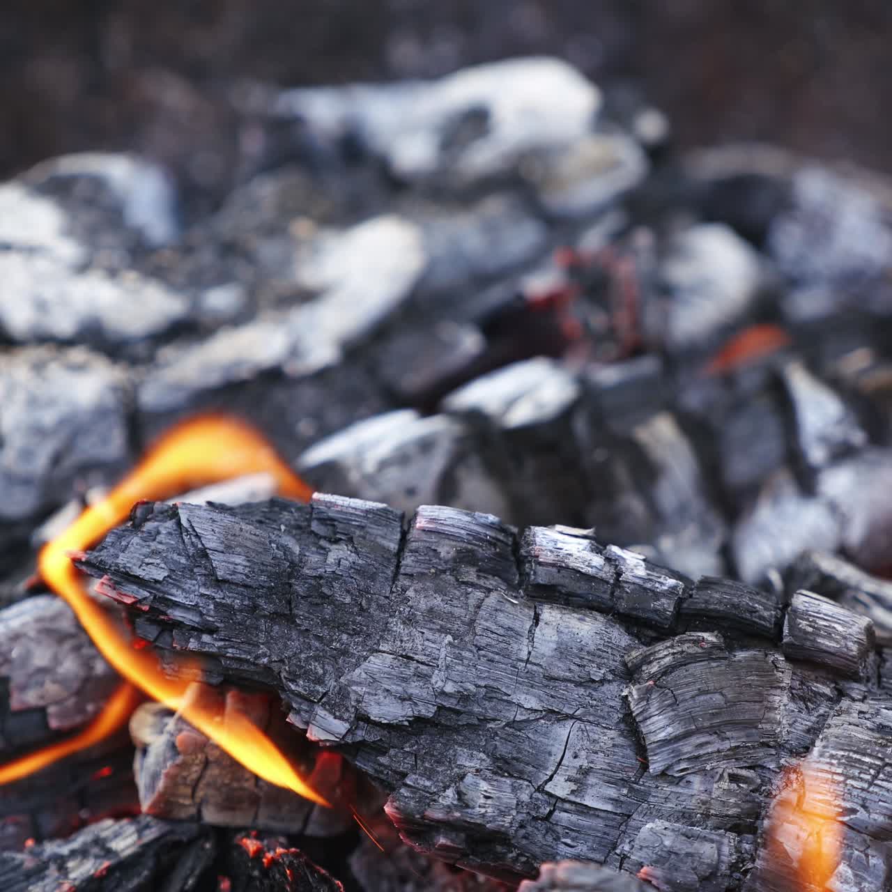 Smoldered logs in fire. Detailed sparkles of flame. Bonfire tongues of flame. Orange fire with bright sparkles. Wood in bright flame. Close-up.