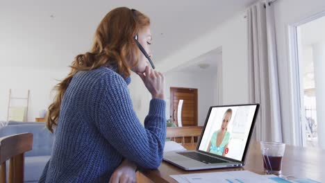 mujer caucásica usando portátil y auriculares de teléfono en videollamada con una colega