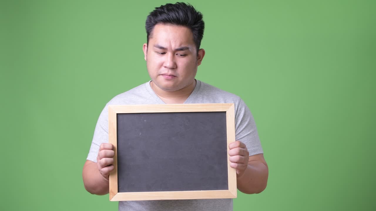 초록색 배경에 젊은 잘생긴 과체중 아시아인