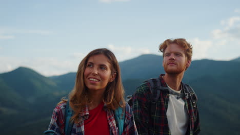 pareja sonriente caminando montañas de verano de cerca. jóvenes viajeros exploran la naturaleza