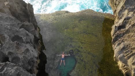 aerial fly over of man in angels billabong tilt up to setting sun over cliffs