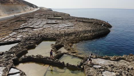 An-aerial-drone-shot-as-people-walk-among-the-rock-Salt-Pans-on-Gozo-Island-in-Malta