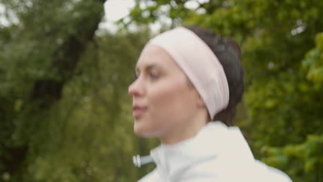 vue rapprochée d'une femme portant un bandeau sur la tête faisant de l'exercice pour rester en forme en courant à la campagne ou dans un parc 2