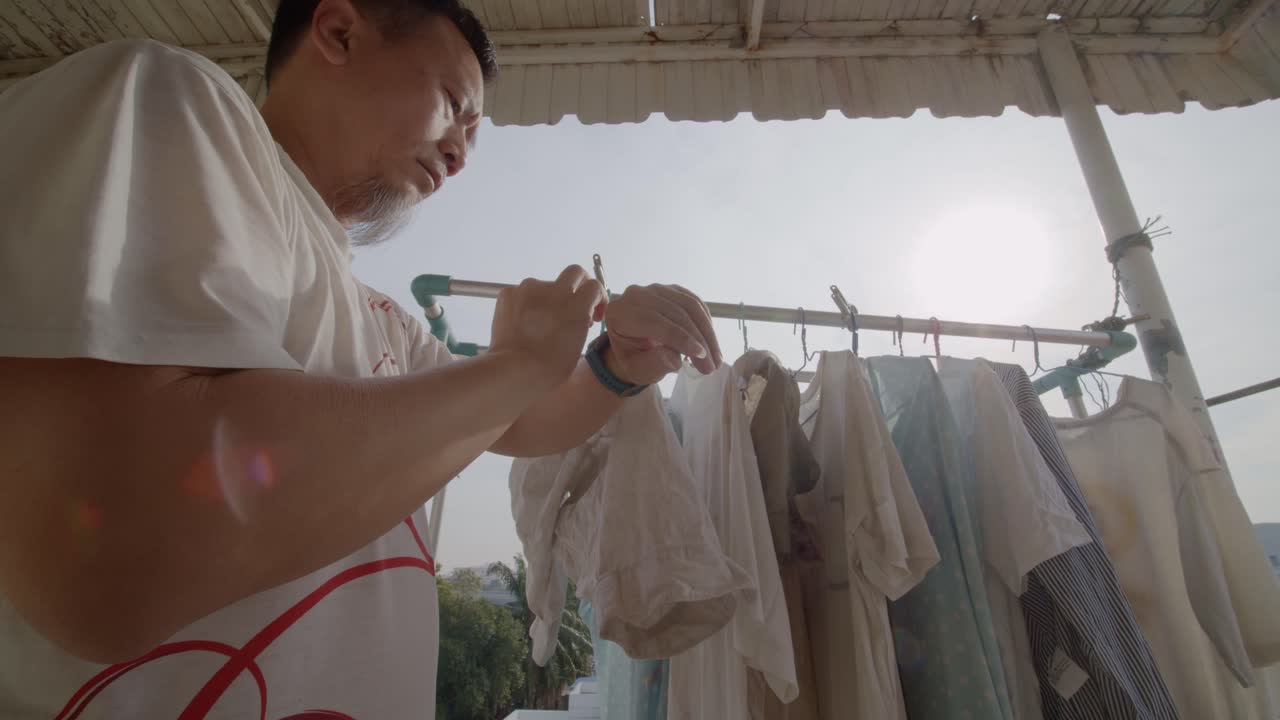 아시아 남자는 발코니에서 옷을 걸고 건조시킨 다음 타이머를 설정합니다 - 슬로우 모션