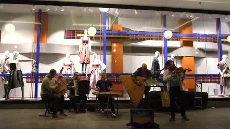 street musicians perform in munich, germany, at night, playing for passersby and hoping for donations, as people stroll through the vibrant city streets.