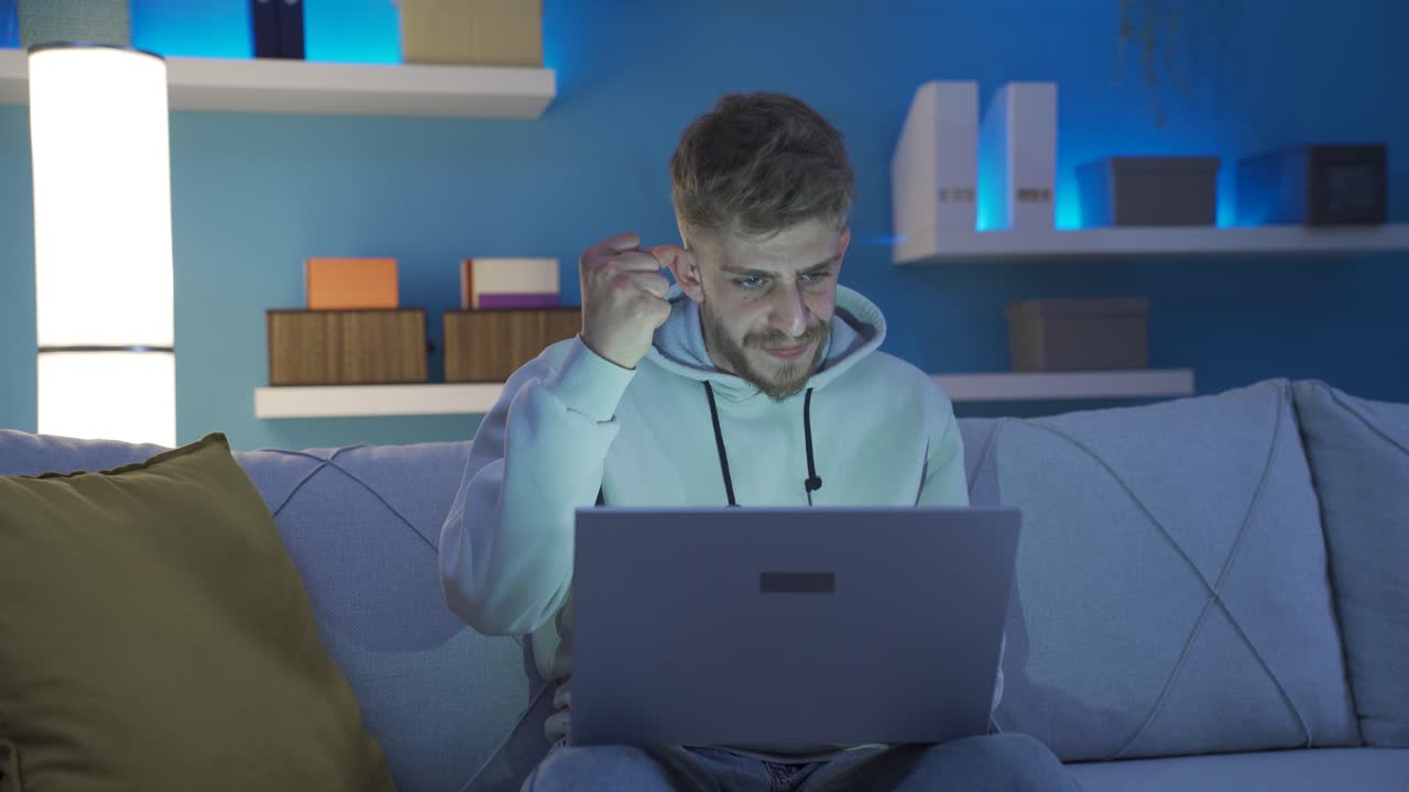 el joven que usa la computadora portátil se sorprende por las malas noticias y comienza a enojarse.