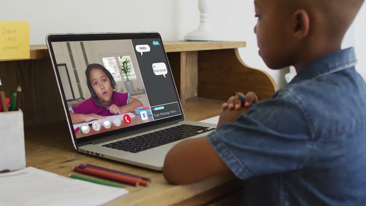 Schoolboy using laptop for online lesson at home, with his colleague and web chat on screen