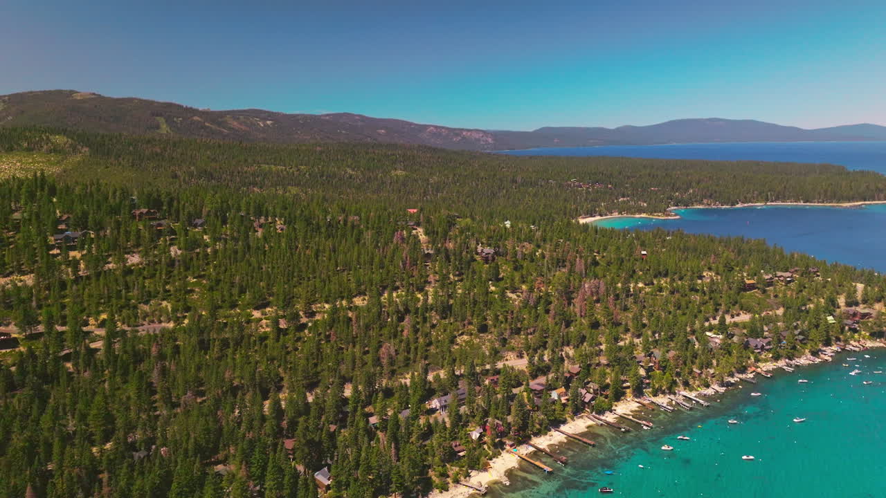 Splendid nature scenery of thick pine tree forest. Private houses situated among the trees. Blue lake surrounded by mountains. Top view.