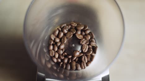 top view of aromatic coffee beans grinding and crushing through ceramic burrs and swirling inside coffee basket