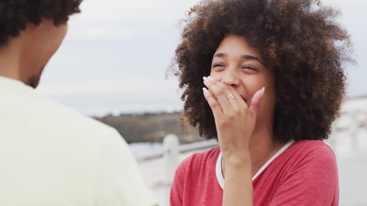 mujer afroamericana sonriendo mientras hablaba con su marido en el paseo cerca de la playa
