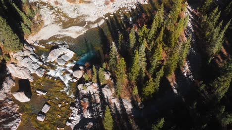 river and waterfall flowing through forest in nordegg seen by drone ascent