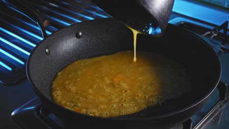 pouring raw beaten eggs into hot skillet, then tortilla wrap on top