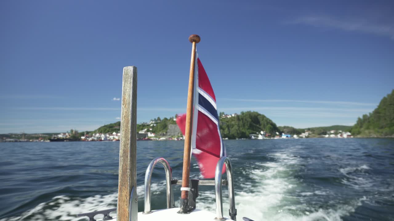 Norwegian flag waving in the wind on the back of speedboat, Norway fjords