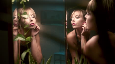 woman applying makeup in front of a mirror at night
