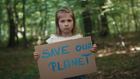 Portrait-of-little-girl-holding-poster-in-the-forest.