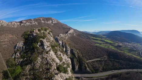 fpv drone aerial image taken from the top of a towering stone mountain, a calming natural image with shades of green, grey, and blue sky