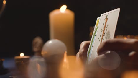 Nahaufnahme-Einer-Frau,-Die-Am-Kerzenbeleuchteten-Tisch-6-Eine-Tarotkarte-Liest