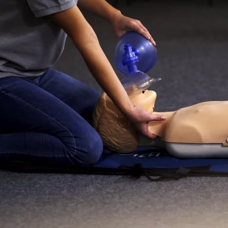 instructor demonstrates breathing exercise on a mannequin. woman on a mat on the floor over the dummy giving a medical training