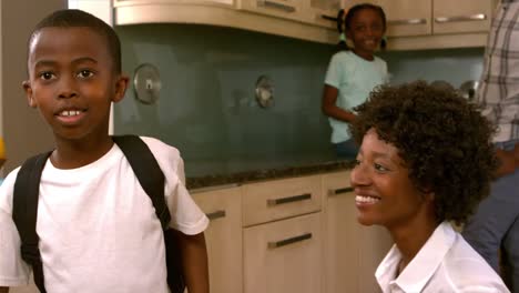 smiling mother kissing son ready for school