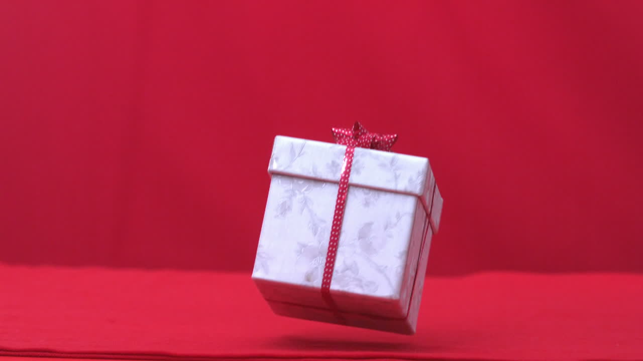 Christmas gift falling and bouncing on red background