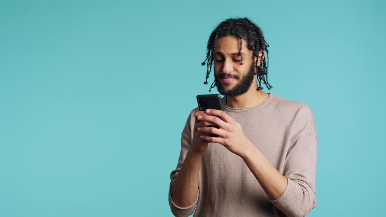 uomo che manda un messaggio a un amico usando uno smartphone, che ride di uno scherzo divertente, sullo sfondo dello studio