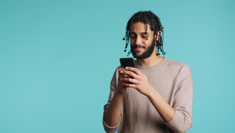 Man-texting-friend-using-smartphone,-laughing-at-funny-joke,-studio-background