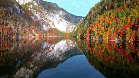 Toma-Panorámica-Lenta-De-Un-Lago-Con-Aguas-Tranquilas-Que-Reflejan-La-Imagen-Especular-Del-Bosque-Y-Las-Montañas-Sobre-él.