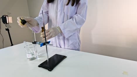 a scientist conducts a chemical reaction using lead nitrate and potassium iodide in a laboratory setting with controlled lighting