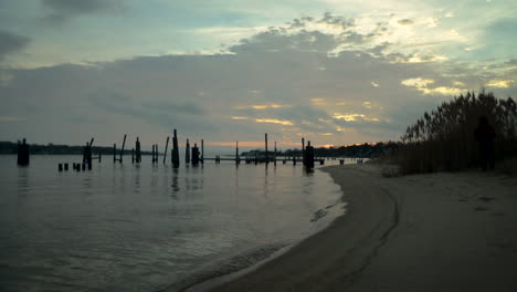 Sunset-behind-a-dilapidated-wooden-pier-on-calm-waters