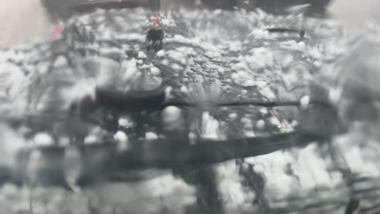 폭풍우가 치는 동안 멈춘 검은색 지프차의 후드 위의 우박 알갱이와 폭우