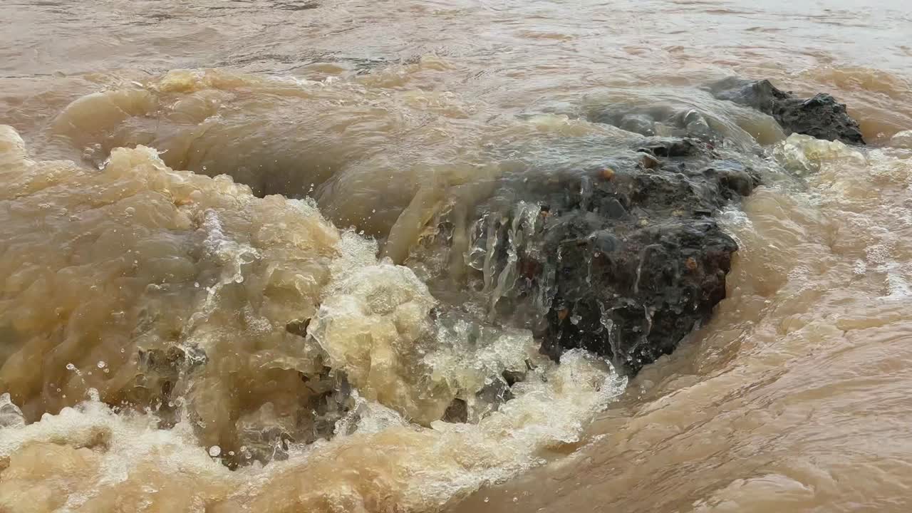 Static shot showing the infrastructure failures, collapsed Bridge or Dam on the river as turbulent, muddy water flowing rapidly indicating floods caused by heavy rainfall, storm runoff