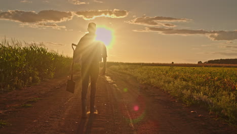 granjero caminando por un camino de tierra durante la puesta del sol