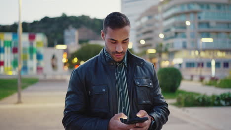 Un-Joven-Vestido-De-Manera-Informal-Usando-Un-Teléfono-Móvil-Al-Aire-Libre.