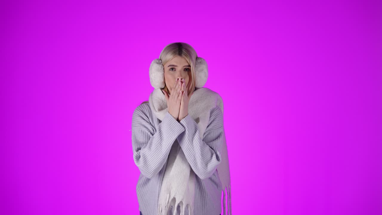 женщина носит плюшевый обогреватель для ушей и шарф, протирает руки от холода, студия