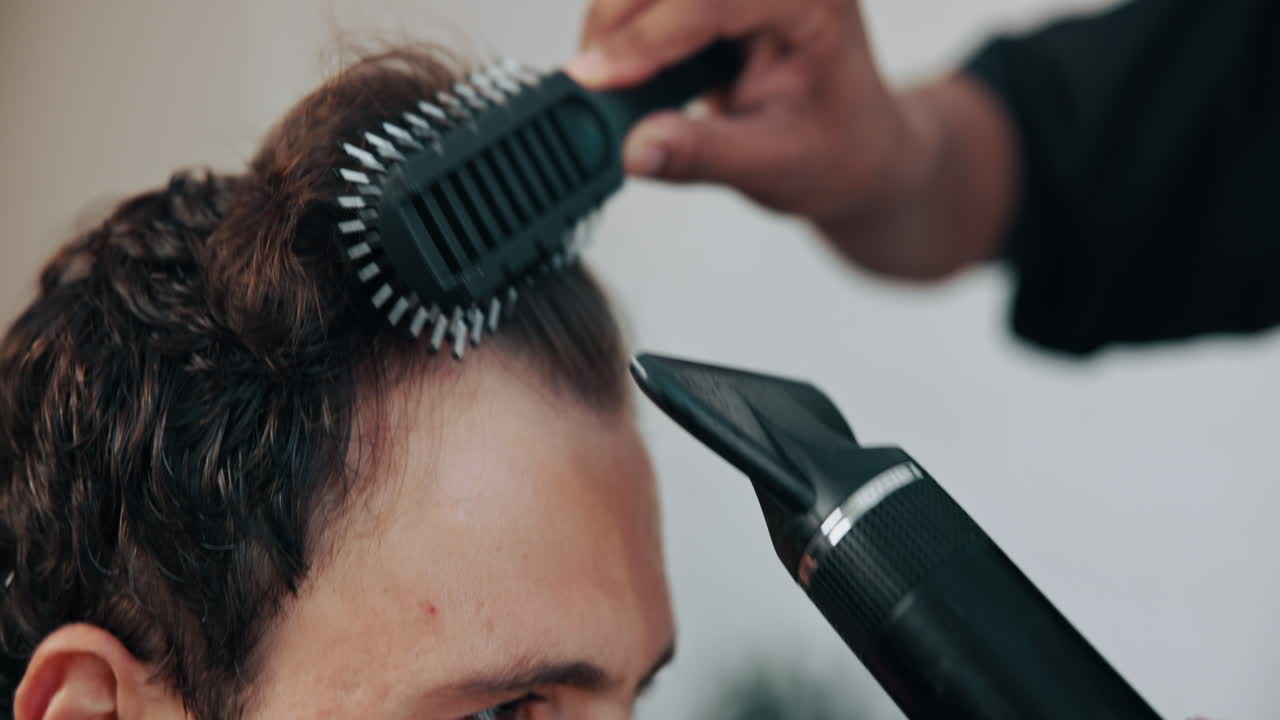 Uomo che si fa acconciare i capelli con phon e spazzola in salone