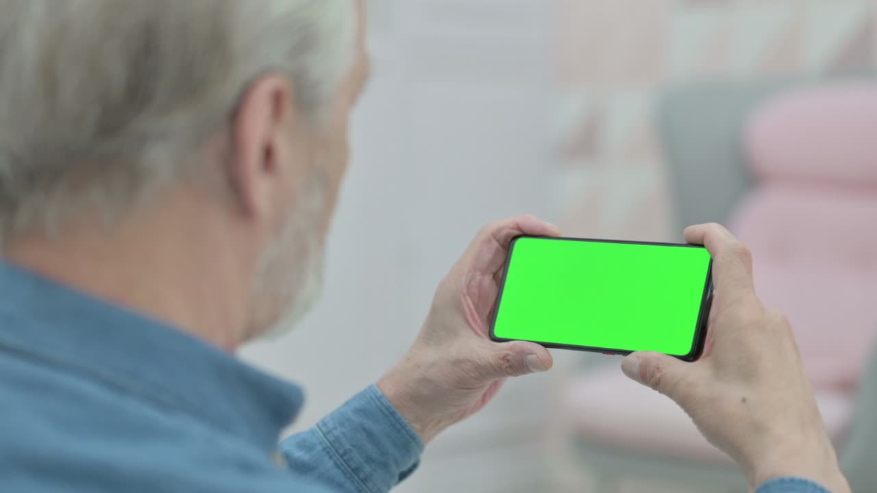 크로마 키 스크린 을 가진 스마트폰 을 사용하는 노인 의 뒷면