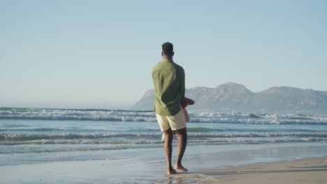 feliz padre afroamericano jugando con su hijo en una playa soleada