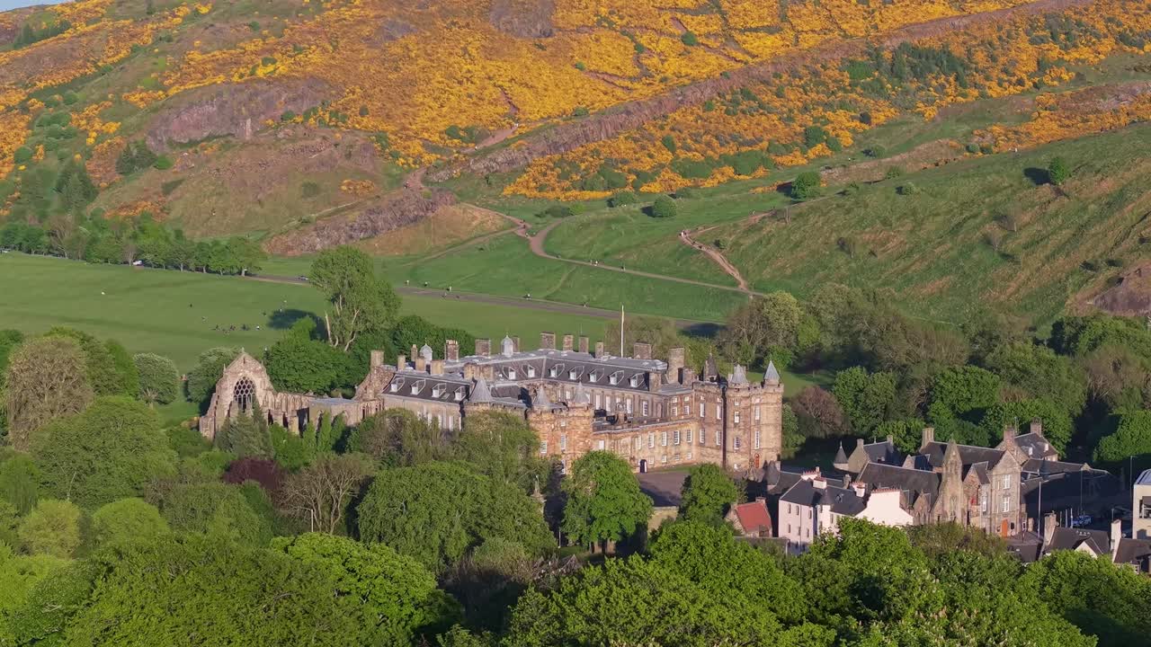 Le riprese con drone rivelano il Palazzo di Holyroodhouse tra gli alberi, svelando gradualmente la residenza reale con Holyrood Park che si erge nello sfondo scenografico