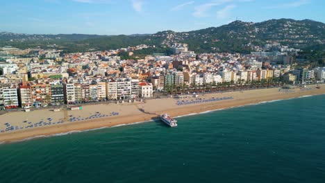 aire de la playa principal de lloret de mar grabado con un barco de pasajeros no tripulado, personas abordando en la playa