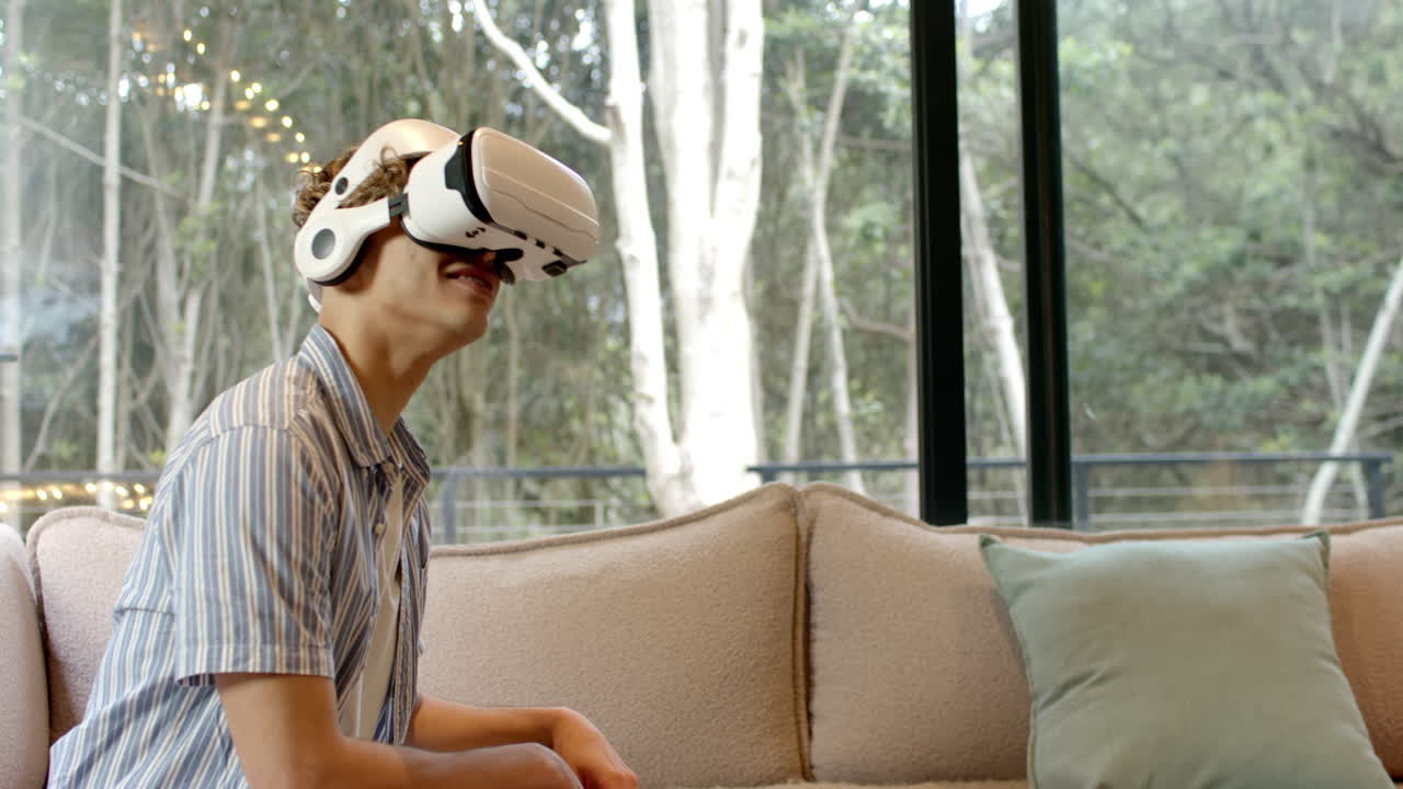 At home, young man using VR headset on sofa, enjoying virtual experience, copy space