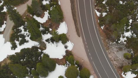 Top-down-revealing-shot-of-a-road-in-the-snowy-mountains-in-Austria