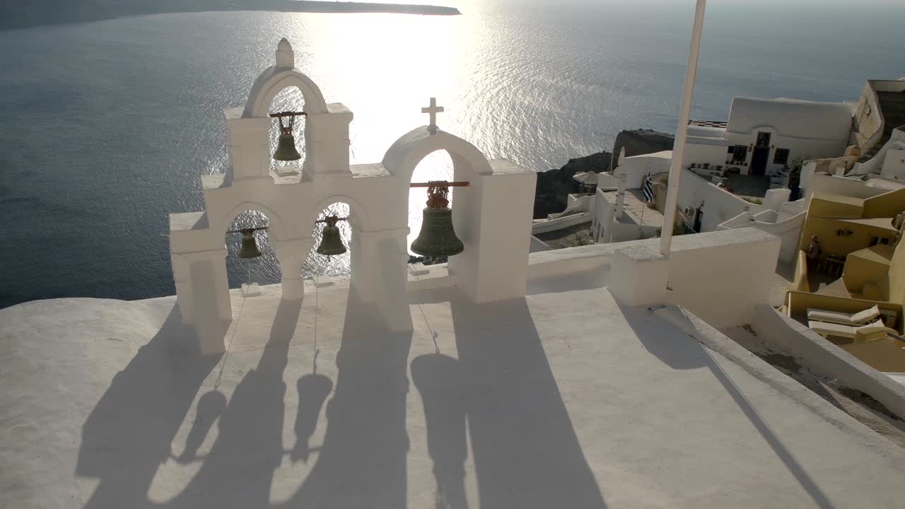 cuatro campanas y sombras al atardecer en oia, santorini
