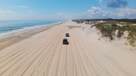 Dron-Siguiendo-Un-Todoterreno-Negro-Y-Un-Camión-Plateado-En-La-Playa-Corolla-4x4-De-Los-Bancos-Exteriores